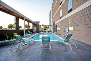 a patio with chairs and a swimming pool at Home2 Suites By Hilton Fort Worth Fossil Creek in Fort Worth
