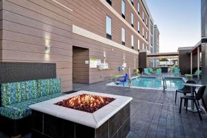 un patio avec un foyer extérieur à côté d'une piscine dans l'établissement Home2 Suites By Hilton Fort Worth Fossil Creek, à Fort Worth