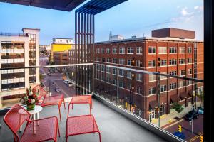 uma varanda com cadeiras vermelhas e uma mesa e edifícios em Canopy By Hilton Grand Rapids Downtown em Grand Rapids