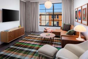 a living room with a couch and a tv at Canopy By Hilton Grand Rapids Downtown in Grand Rapids