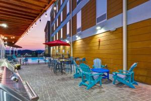 a patio with blue chairs and tables on a building at Home2 Suites By Hilton Hot Springs in Hot Springs