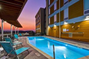 a swimming pool with chairs and a building at Home2 Suites By Hilton Hot Springs in Hot Springs