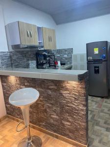 uma cozinha com um balcão com um banco e um frigorífico em Confortable Apartamento Central em Tame