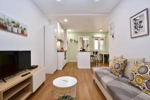 ein Wohnzimmer mit einem Sofa und einem TV sowie eine Küche in der Unterkunft STAY Rosal in Oviedo