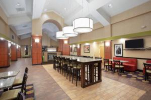 a large room with a bar and tables and chairs at Hampton Inn & Suites Kansas City-Merriam in Merriam