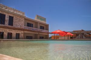 a hotel with a swimming pool with a red umbrella at Hotel Scappata in Progreso
