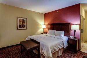 a hotel room with a large bed with white sheets at Hampton Inn Junction City in Junction City