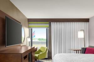 a hotel room with a television and a bed and a desk at Hampton Inn Milwaukee Brookfield in Brookfield