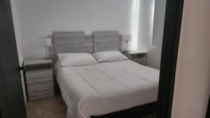 a bedroom with a white bed with two night stands at DEPARTAMENTOS CIELO DE CAFAYATE in Cafayate