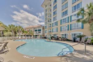 een zwembad met stoelen en een groot gebouw bij Hampton Inn Myrtle Beach Broadway at the Beach in Myrtle Beach