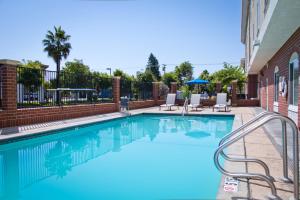 una piscina con 2 sillas y un edificio en Holiday Inn Express & Suites Sacramento NE Cal Expo, an IHG Hotel, en Sacramento