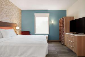 a bedroom with a bed and a flat screen tv at Home2 Suites By Hilton Warminster Horsham in Warminster