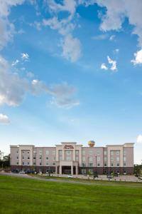 un gran edificio con un campo verde delante de él en Hampton Inn & Suites Denison, en Denison