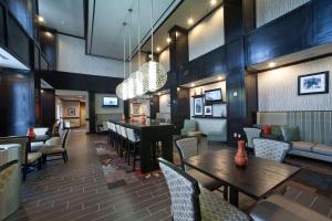 a restaurant with tables and chairs and a bar at Hampton Inn & Suites Denison in Denison