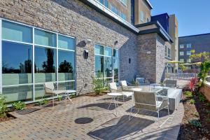 a patio with chairs and tables in front of a brick building at Hampton Inn Chula Vista Eastlake in Chula Vista