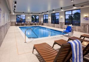 - une piscine dans une chambre d'hôtel dotée de bancs et de chaises dans l'établissement Hampton Inn Spicer Green Lake, MN, à Spicer
