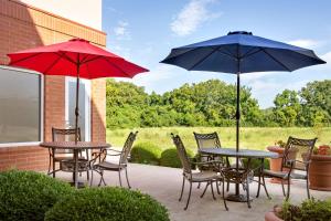 2 Tische und Stühle mit Sonnenschirmen auf einer Terrasse in der Unterkunft Hampton Inn St. Louis-Columbia in Millstadt Junction