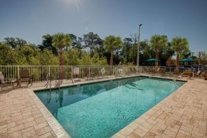 a swimming pool with chairs and a fence at Hampton Inn Plant City in Plant City