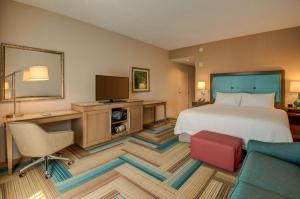 Habitación de hotel con cama y escritorio con TV. en Hampton Inn Plant City, en Plant City