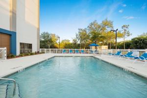 une piscine avec des chaises bleues et un bâtiment dans l'établissement Hampton Inn Tampa-Veterans Expressway, à Tampa