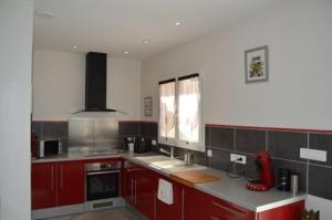a kitchen with red cabinets and a counter top at maison zen 60m2 proche Aubenas le Baya in Ucel