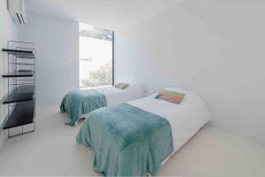 Contemporary Beach House Cabedelo في فيانا دو كاستيلو: سريرين في غرفة بيضاء مع نافذة
