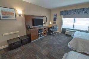 um quarto de hotel com uma cama e uma secretária com uma televisão em Hampton Inn & Suites Chesapeake-Battlefield Boulevard em Chesapeake