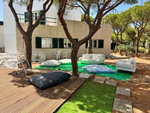 una terraza con almohadas y un árbol frente a una casa en CASA DOS CATOS, en Praia Verde