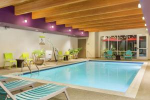 a swimming pool in a hotel with chairs and tables at Home2 Suites by Hilton Canton in North Canton