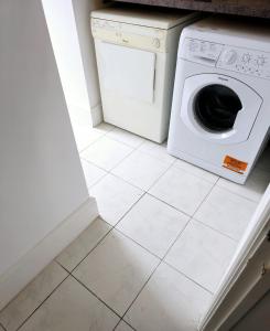 uma máquina de lavar e secar roupa branca sentada num piso de azulejo em The Private Rooms in Paddington em Londres