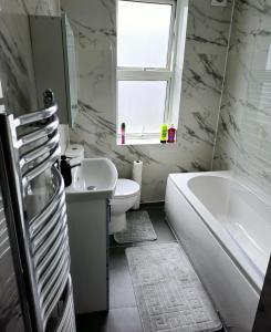 a bathroom with a tub and a toilet and a sink at The Private Rooms in Paddington in London