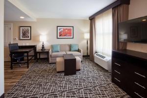 ein Hotelzimmer mit einem Sofa, einem Tisch und einem Schreibtisch in der Unterkunft Homewood Suites Davenport in Bettendorf