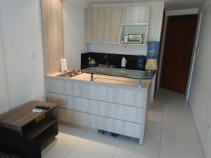 eine Küche mit einer Theke mit Spüle und Mikrowelle in der Unterkunft Flat de frente ao mar in Conde