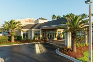 a hotel with palm trees in front of a building at Hilton Garden Inn Saint Augustine Beach in Saint Augustine Beach