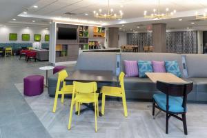 a waiting area with yellow chairs and tables and a couch at Home2 Suites By Hilton Indianapolis Airport in Indianapolis