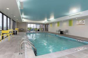 a pool in a building with tables and chairs at Home2 Suites By Hilton Indianapolis Airport in Indianapolis