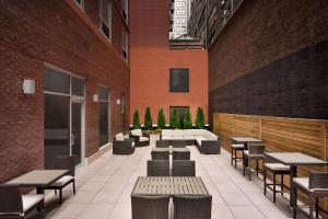 eine Terrasse mit Tischen und Stühlen in einem Gebäude in der Unterkunft Hilton Garden Inn New York Times Square South in New York