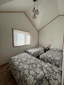 two beds in a small bedroom with a window at Cabañas Nevados Del Valle in Malalcahuello