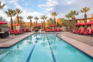 una piscina en un hotel con sillas rojas y palmeras en Hilton Grand Vacations Club Palm Desert en Palm Desert