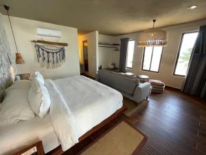 a bedroom with a large white bed and a couch at Hotel Scappata in Progreso