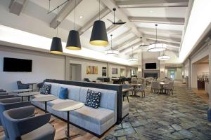 a waiting room with tables and chairs and a couch at Homewood Suites by Hilton Albany in Albany