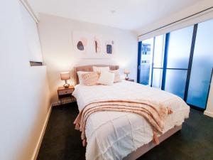 een slaapkamer met een bed en een groot raam bij Adelaide City Loft in Adelaide