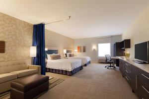 オクラホマシティにあるHome2 Suites by Hilton Oklahoma City Southのベッドとデスクが備わるホテルルームです。