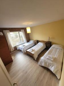 a bedroom with three beds and a window at Casa Lago Argentino in El Calafate