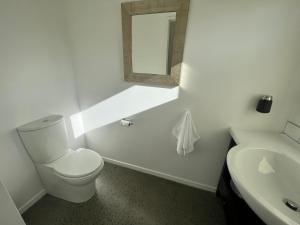 a white bathroom with a toilet and a sink at Mary Hut in Lake Tekapo
