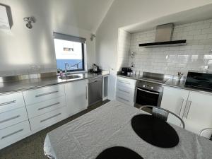 a kitchen with white cabinets and a table and a sink at Mary Hut in Lake Tekapo +4 photos