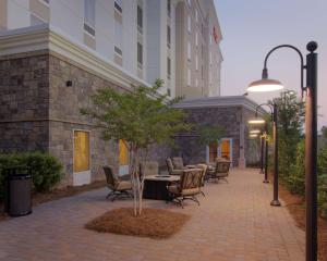 un patio con tavoli e sedie di fronte a un edificio di Hampton Inn & Suites Raleigh-Durham Airport-Brier Creek a Raleigh