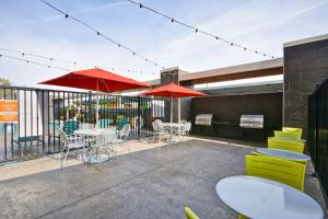 a patio with tables and chairs and red umbrellas at Home2 Suites By Hilton Hanford Lemoore in Hanford
