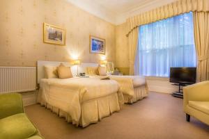 um quarto de hotel com duas camas e uma televisão em Balincourt em Bournemouth