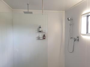 a white bathroom with a shower with a glass door at Shargmor Stable in Matamata